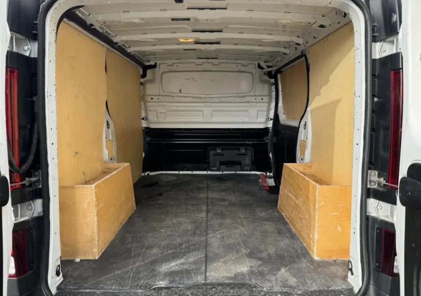 Vue arrière intérieure du fourgon blanc Nissan Primastar 2022 avec plancher et protections latérales en bois.