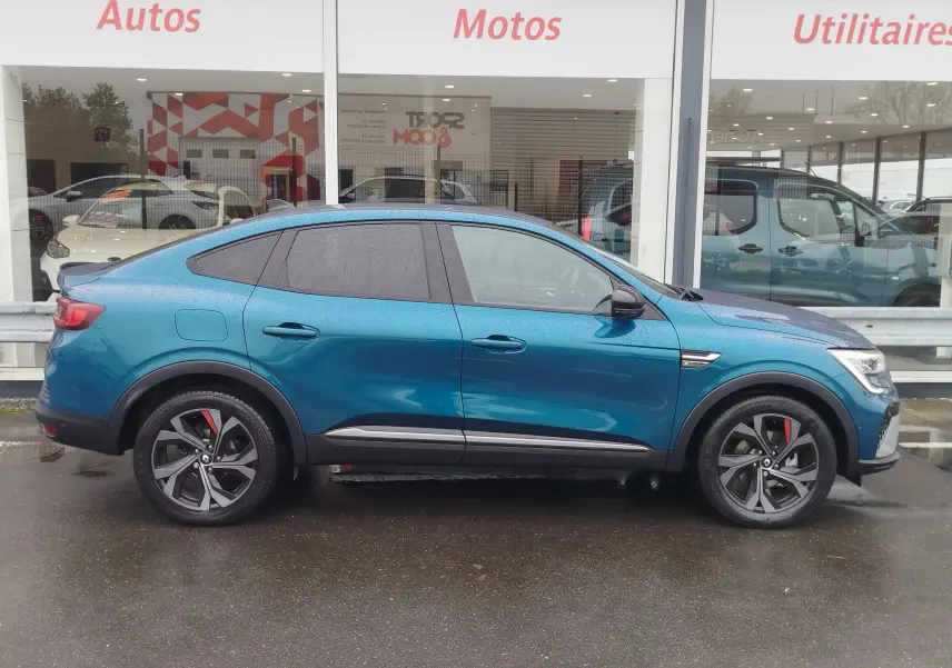 Vue de profil côté gauche d'un Renault Arkana bleu Zanzibar 2022 avec jantes noires et détails rouges sur les étriers.