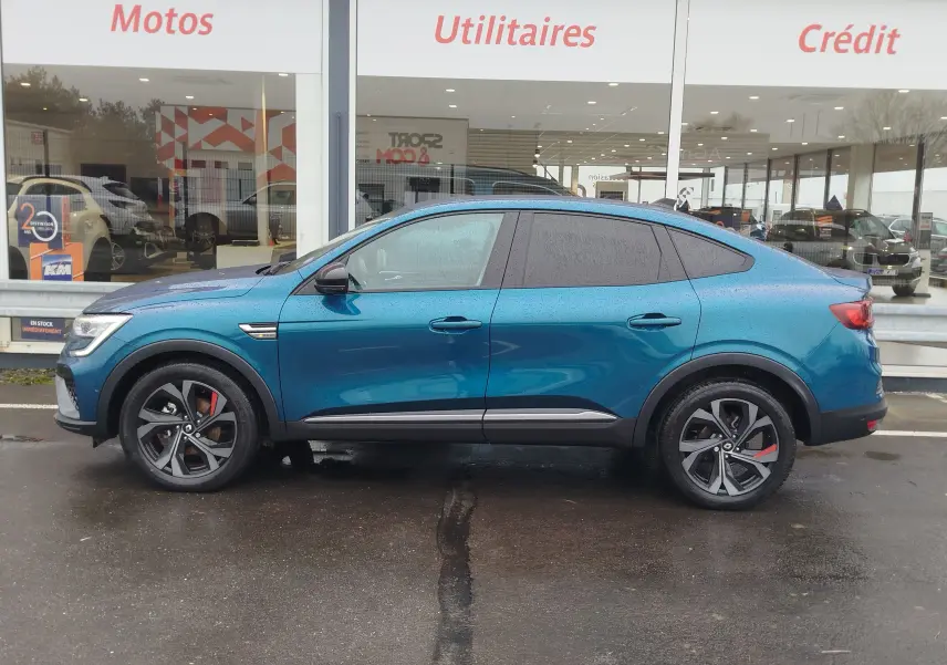 Profil côté gauche d'une Renault Arkana 1.6 E-Tech bleu Zanzibar 2022 avec jantes noires et étriers rouges.