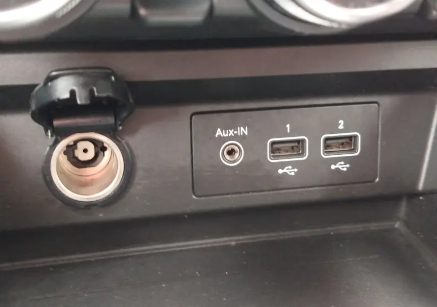 Détail intérieur du Renault Arkana 2022 montrant une prise allume-cigare ouverte, une entrée Aux-IN et deux ports USB.