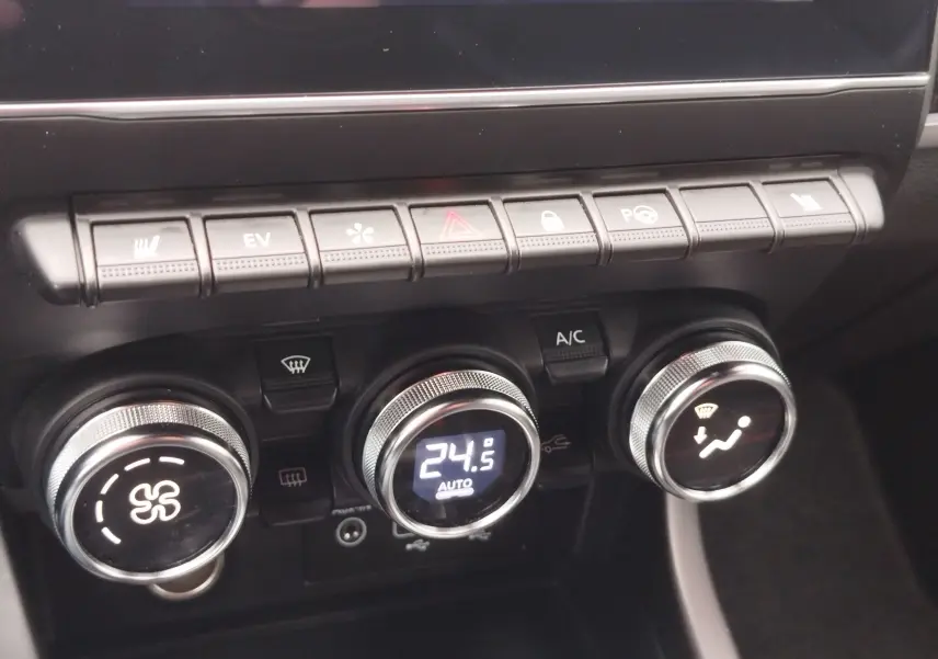 Gros plan sur la console centrale du Renault Arkana 1.6 E-Tech, montrant les commandes de climatisation et les boutons de fonction.