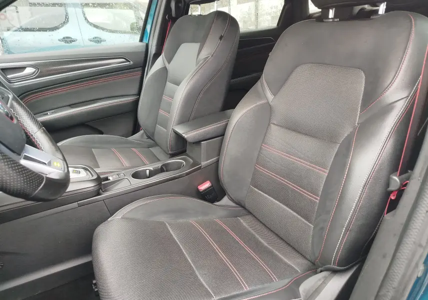 Vue intérieure côté conducteur du Renault Arkana bleu Zanzibar, sièges noirs en cuir et tissu avec surpiqûres rouges.