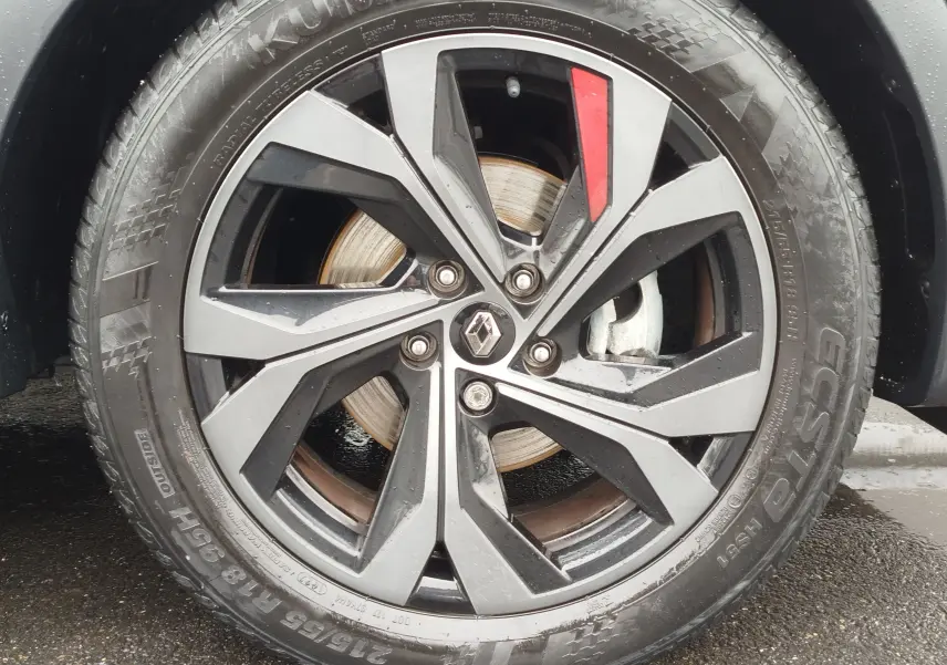 Gros plan sur la jante noire et grise avec un détail rouge du Renault Arkana bleu Zanzibar, roue avant droite.