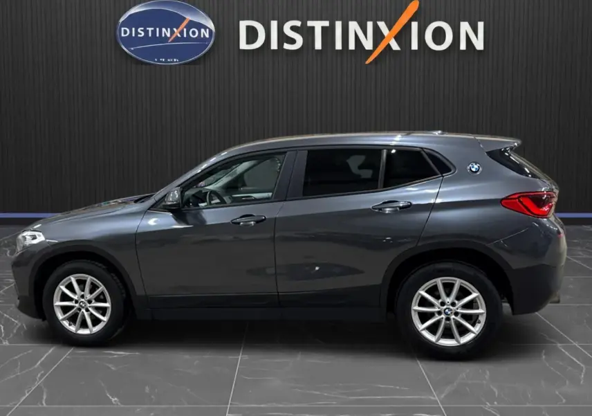 BMW X2 gris minéral métallisé vue de profil côté gauche, vitres arrière surteintées et jantes alliage visibles.