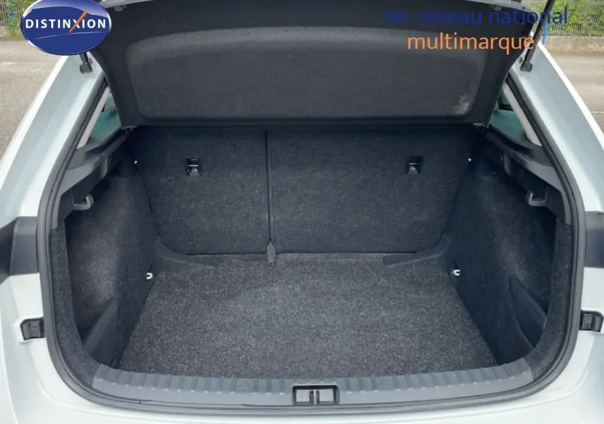 Coffre ouvert d'une Skoda Scala blanc glacier, vue arrière montrant l'espace de chargement vide et tapissé de tissu gris.