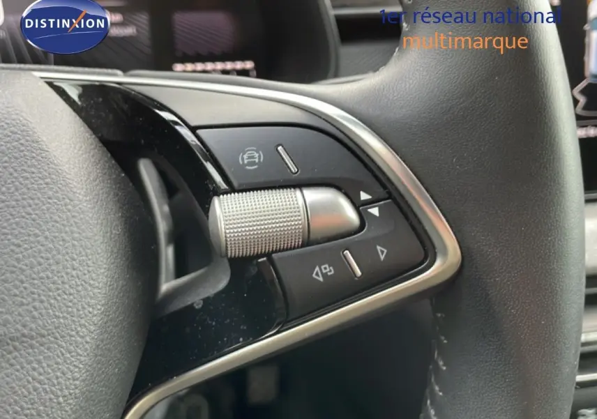 Gros plan sur les commandes multifonctions à droite du volant cuir noir d'une Skoda Scala blanc glacier 2025.