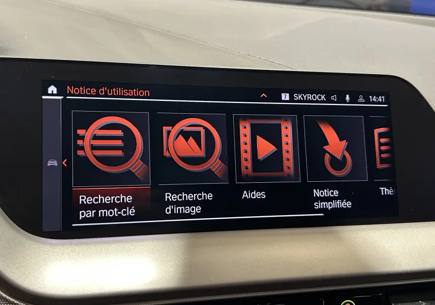 Écran tactile intérieur du système GPS de la BMW Série 1 16d 2023, affichant le menu d'aide en rouge et noir.