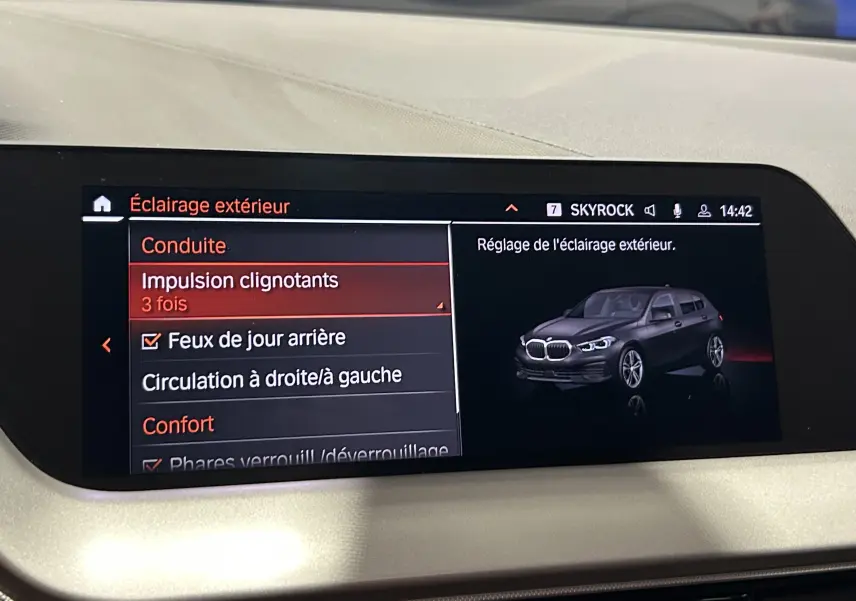 Écran central montrant le menu de réglage de l'éclairage extérieur avec une illustration 3/4 avant d'une BMW Série 1 noire.