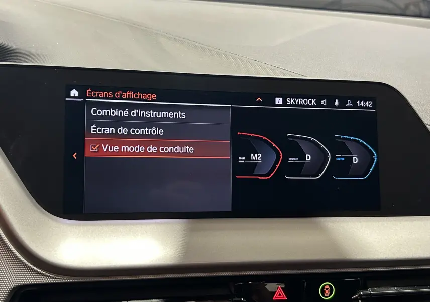 Écran central de la BMW Série 1 16d 2023 affichant les modes de conduite Sport, Confort et Eco en vue intérieure.