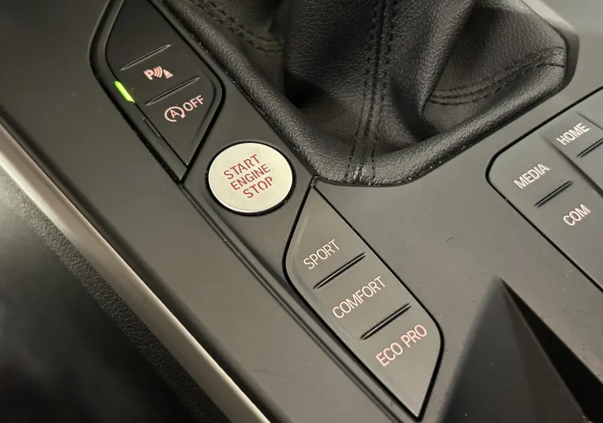 Gros plan sur la console centrale noire de la BMW Série 1 16d 2023, montrant les boutons de mode de conduite et le démarrage moteur.