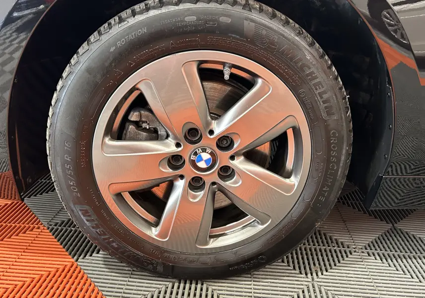 Gros plan sur la roue avant gauche noire d'une BMW Série 1 16d 2023 avec jante alliage et pneu Michelin.