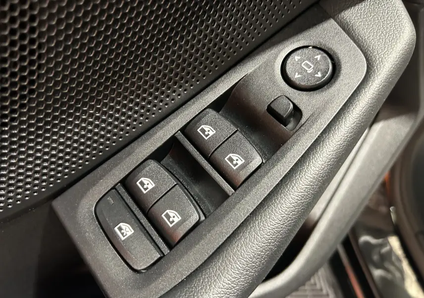 Gros plan sur les commandes de lève-vitres et réglage des rétroviseurs côté conducteur d’une BMW Série 1 noire 2023.