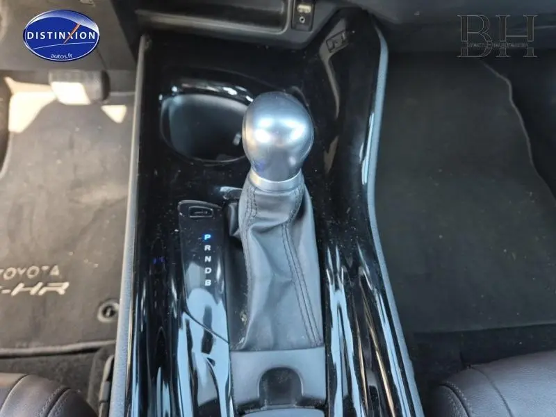 Gros plan sur la console centrale noire brillante du Toyota C-HR gris aluminium, mettant en valeur le levier de vitesse automatique.
