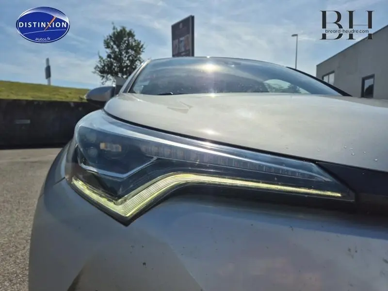 Gros plan sur le phare avant gauche du Toyota C-HR 122h Distinctive gris aluminium, soulignant son design LED distinctif.