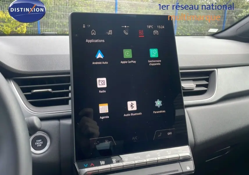 Vue intérieure centrée sur l'écran tactile vertical du tableau de bord du Renault Captur gris Cassiopée, avec commandes climatisation visibles.
