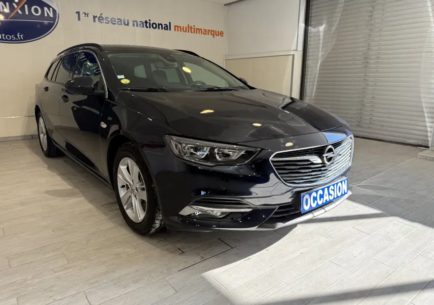 Vue 3/4 avant d'une Opel Insignia Sports Tourer bleu lune marine métal avec calandre chromée en showroom.