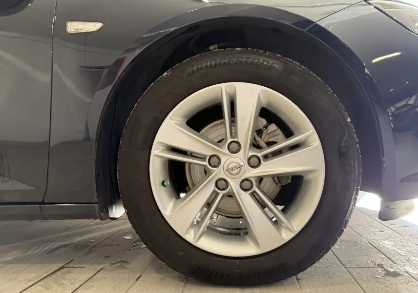Gros plan sur la roue avant droite d'une Opel Insignia Sports Tourer bleu lune marine métal avec jante argentée cinq branches.