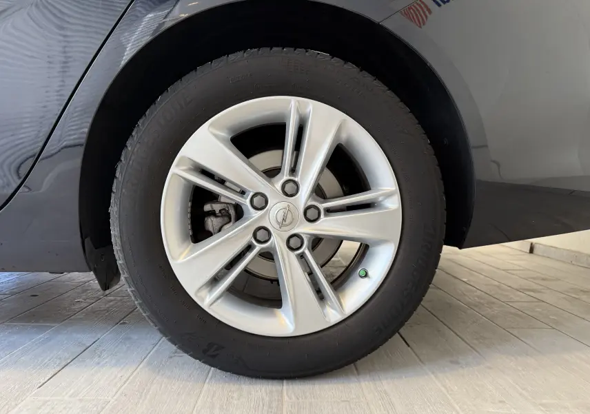 Gros plan sur la roue avant gauche de l'Opel Insignia Sports Tourer bleu lune marine métal avec jante argentée cinq branches.
