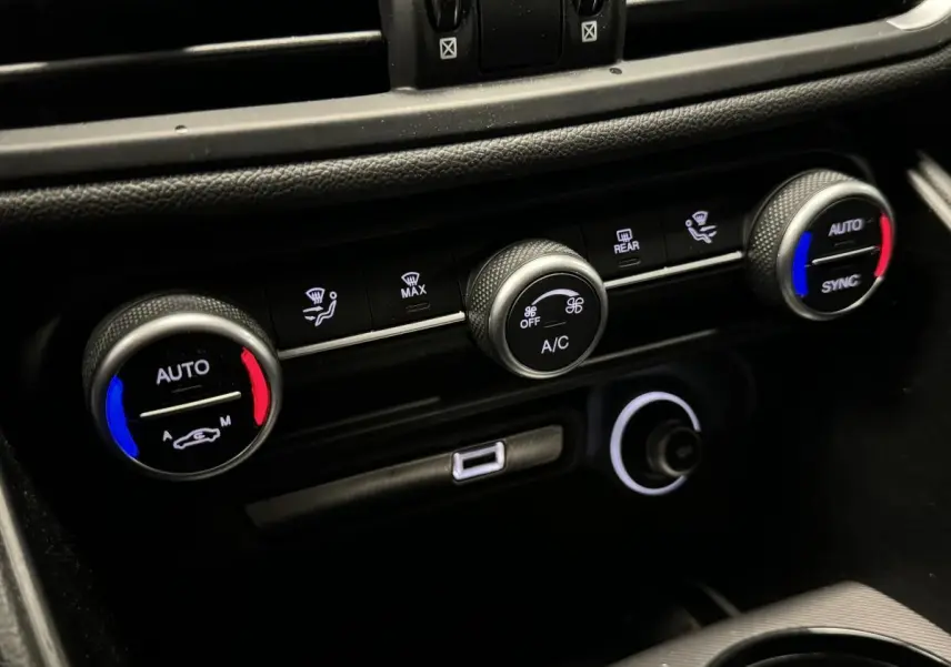 Gros plan sur la console centrale de l'Alfa Romeo Giulia 2021, montrant les commandes de climatisation automatique à réglages colorés.
