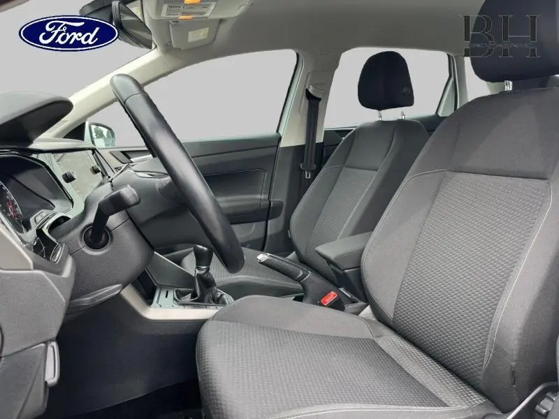 Vue intérieure côté conducteur d'une Volkswagen Polo 1.0 TSI 95ch Lounge Business 2021 avec sièges tissu gris et volant cuir multifonction.