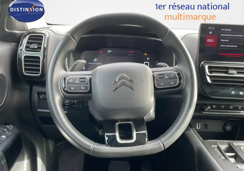 Vue intérieure centrée sur le volant noir du Citroën C5 Aircross 2024 avec tableau de bord digital et écran tactile.
