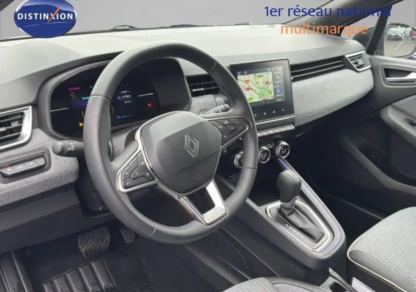 Vue intérieure côté conducteur de la Renault Clio 2025, tableau de bord gris clair avec écran tactile et volant cuir multifonction.
