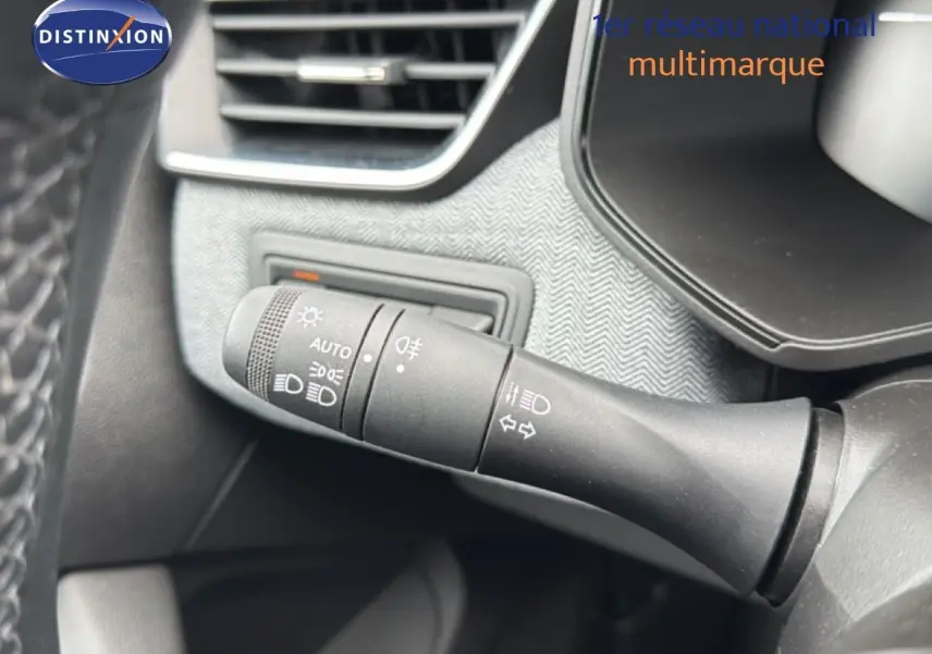 Gros plan sur la commande des phares et clignotants dans l’habitacle gris noir de la Renault Clio hybride 2025.