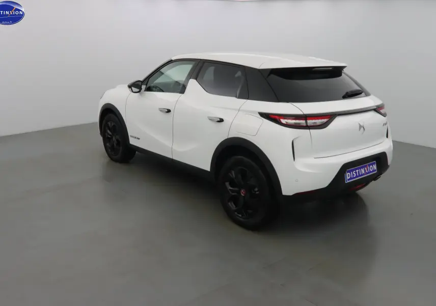 Vue 3/4 arrière droite d'un DS3 Crossback blanc banquise avec jantes noires et toit noir contrasté.