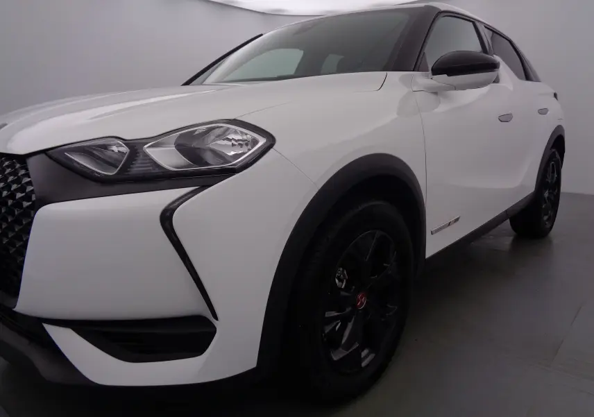 Vue 3/4 avant droit d'un DS3 Crossback blanc banquise avec jantes noires et détails noirs contrastants.