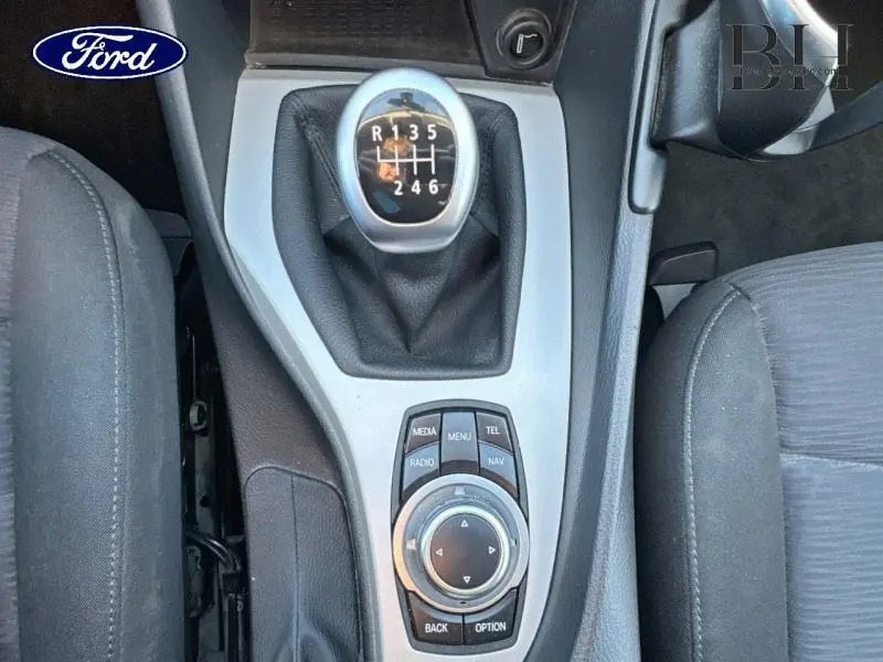 Gros plan sur la console centrale avec levier de vitesse manuel et commandes multimédia, intérieur tissu gris.