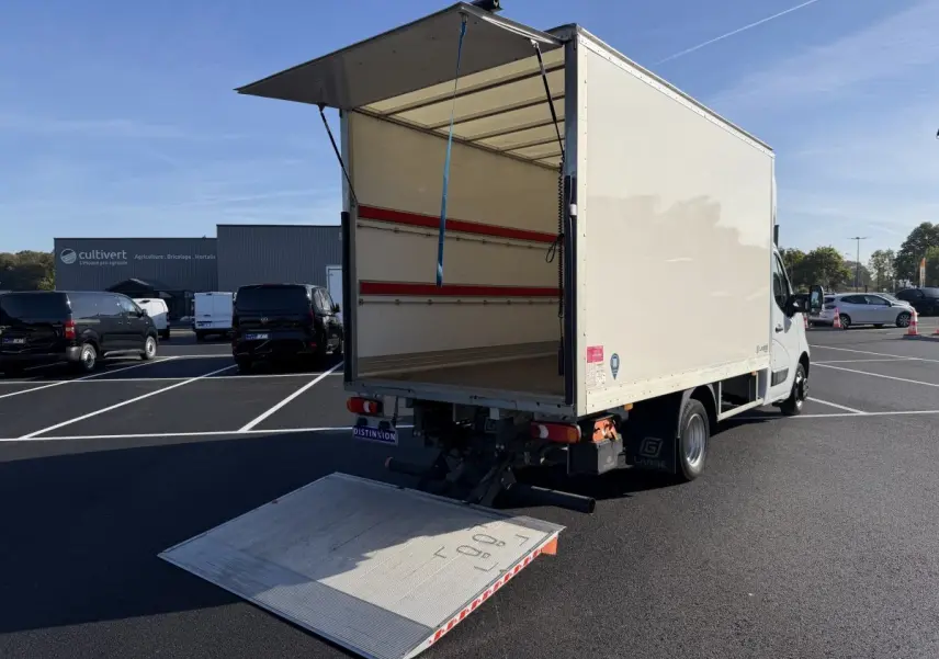 Nissan Interstar blanc vu 3/4 arrière avec hayon élévateur déployé et caisse ouverte sur parking.