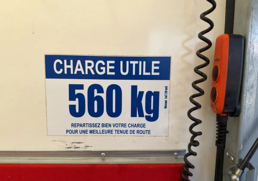 Vue intérieure du hayon d’un utilitaire Nissan Interstar blanc, avec étiquette de charge utile 560 kg et commande rouge.