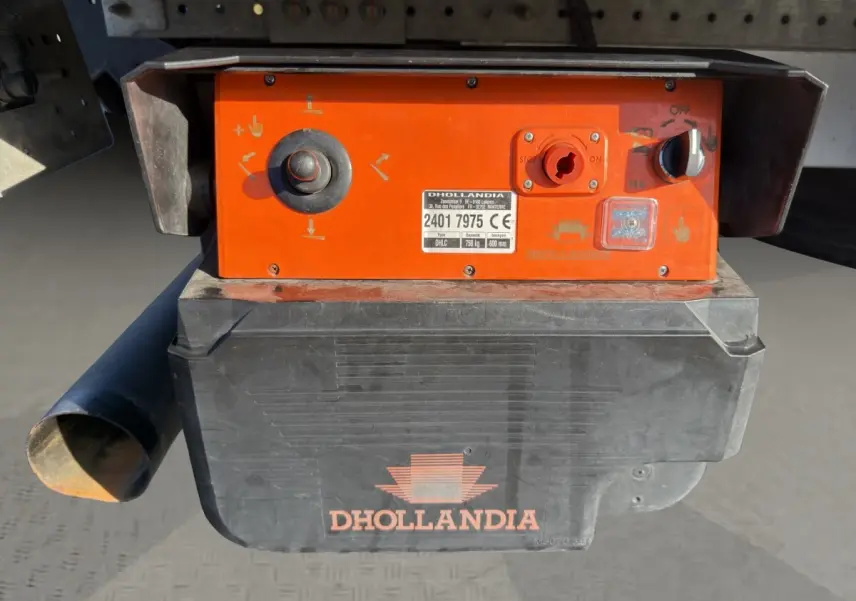 Gros plan sur le boîtier de commande orange et noir du hayon Dhollandia fixé à l'arrière du Nissan Interstar blanc.