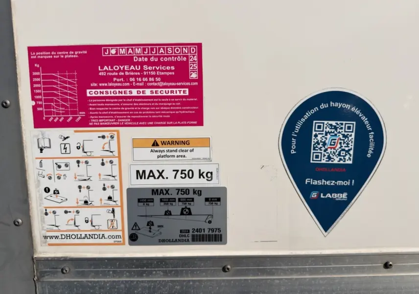 Gros plan sur des autocollants de sécurité et d’utilisation du hayon élévateur sur la caisse blanche d’un Nissan Interstar.