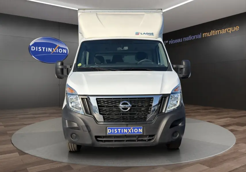 Vue de face du utilitaire blanc Nissan Interstar avec caisse surélevée et pare-chocs noir, en showroom Distinxion.