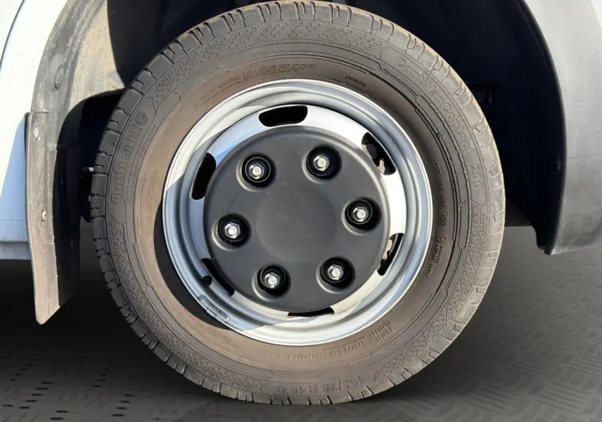 Gros plan sur la roue jumelée avant droite du Nissan Interstar blanc, jante acier avec cache central noir.