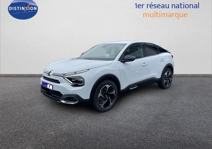 Citroën C4 blanc métal vue 3/4 avant droit avec jantes noires et toit noir contrasté sur sol gris.