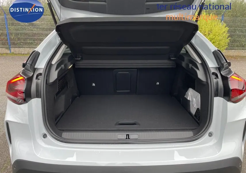 Coffre ouvert vu de l'arrière d'une Citroën C4 blanche métal 2024, montrant l'espace de chargement vide.