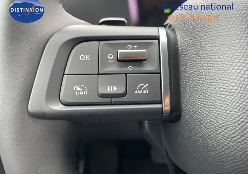 Gros plan sur les commandes au volant de la Citroën C4 blanche métal 2024, avec boutons d'assistance et limitation de vitesse.