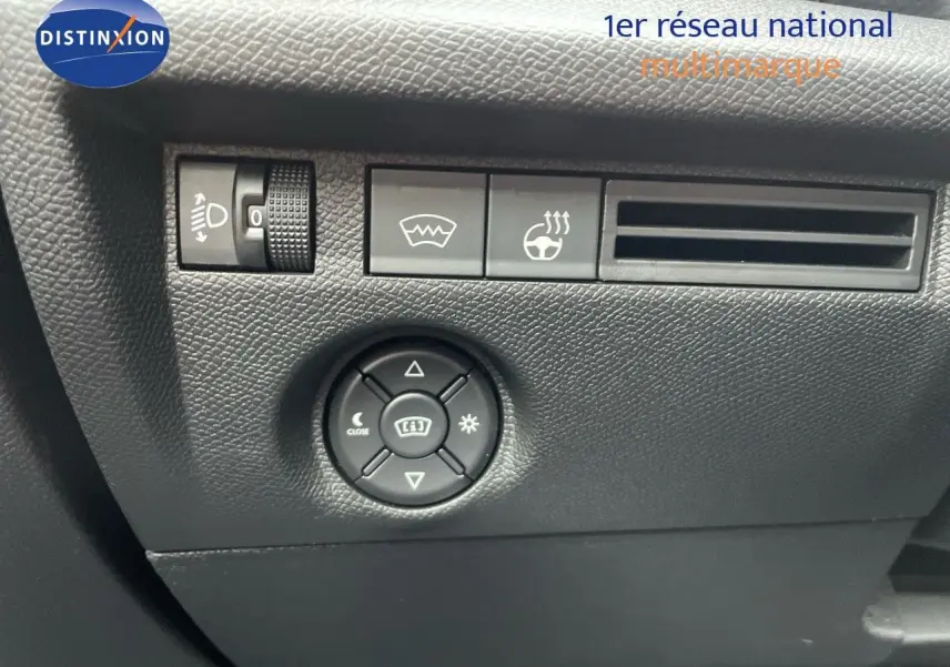 Gros plan sur les commandes de réglage des phares et du volant chauffant dans l'habitacle noir d'une Citroën C4 2024.
