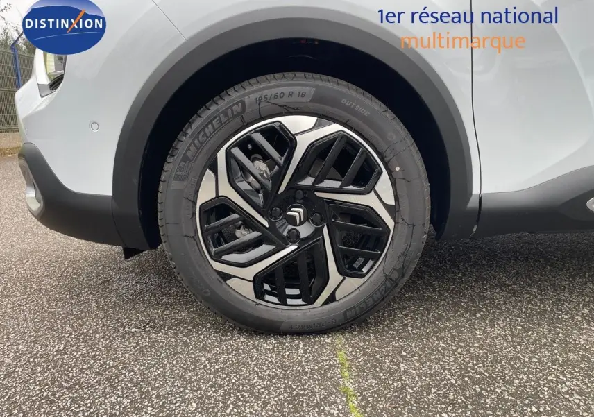 Gros plan sur la roue avant gauche d'une Citroën C4 blanche métal 2024 avec jante alliage bi-ton noire et argent.