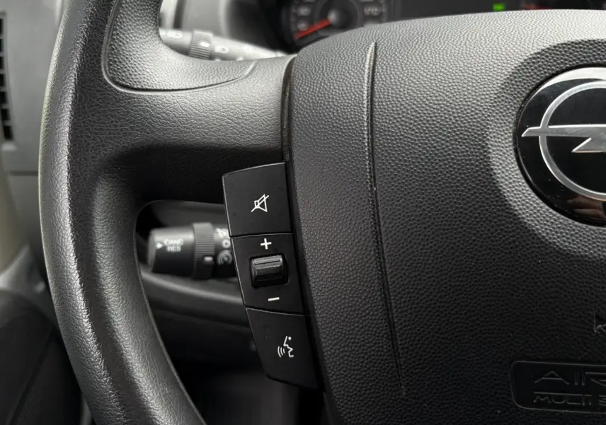 Gros plan sur le volant noir de l'Opel Movano Fourgon 2023 avec commandes audio intégrées visibles.