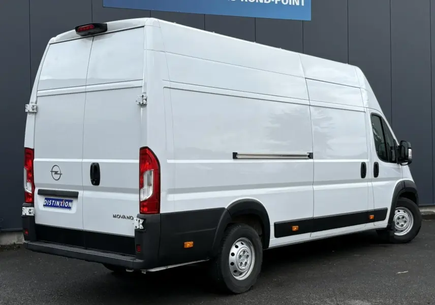 Opel Movano Fourgon blanc vu en 3/4 arrière droit, avec portes arrière battantes et plancher bois visible.