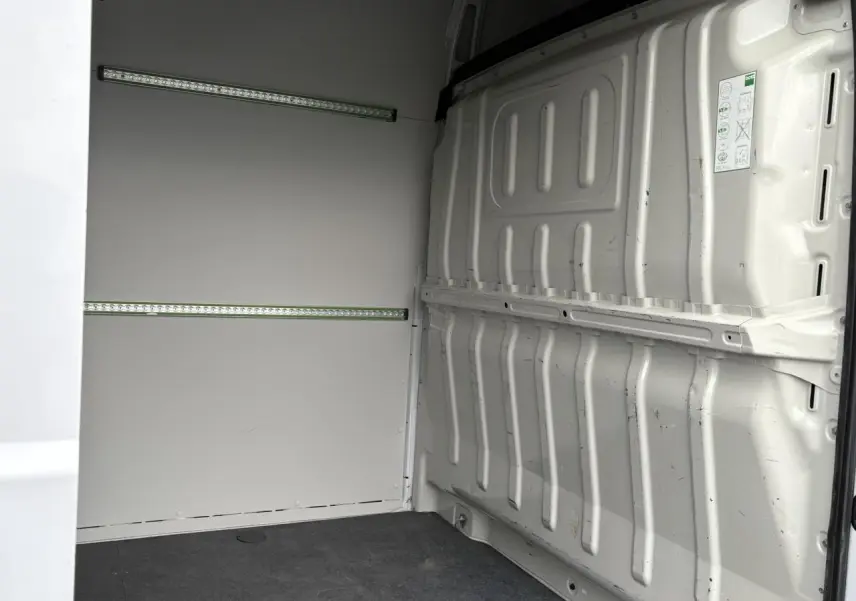 Vue intérieure arrière droite du fourgon Opel Movano blanc avec plancher bois et habillage latéral tôlé.