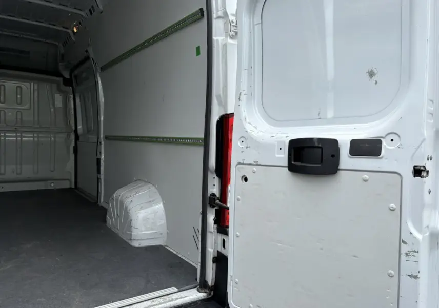 Vue intérieure arrière du fourgon blanc Opel Movano avec plancher et habillage latéraux visibles.