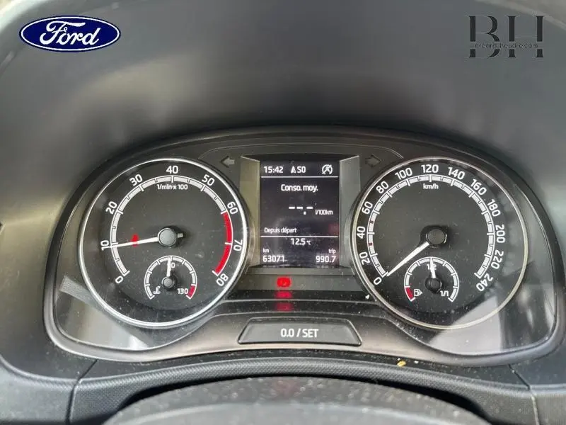 Tableau de bord avec compte-tours et compteur de vitesse en km/h, affichage digital central, intérieur noir.