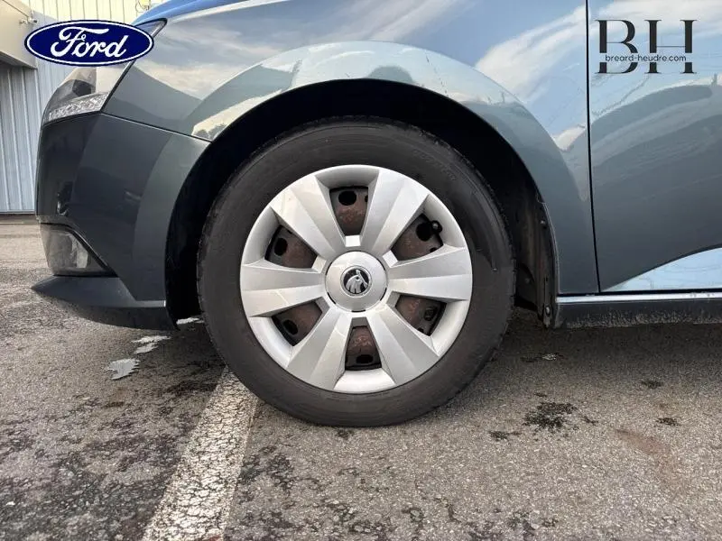 Gros plan sur la roue avant gauche d'une Skoda Fabia gris météore 2021 avec enjoliveur argenté et logo central.