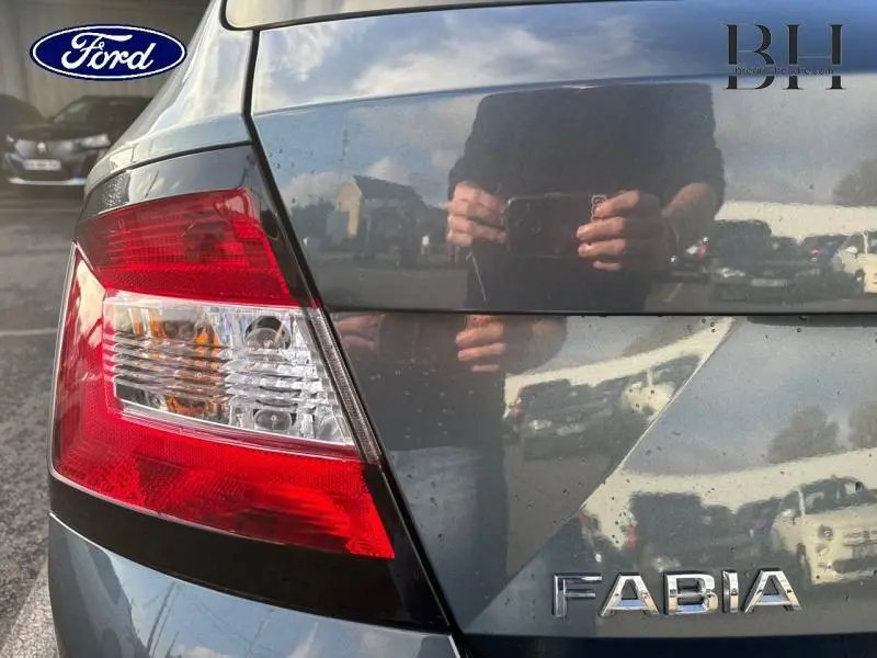 Gros plan sur le feu arrière gauche d'une Skoda Fabia gris météore, avec reflet du photographe sur la carrosserie.