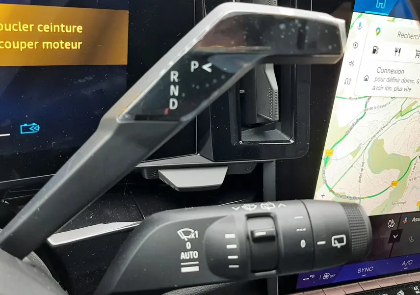 Gros plan sur la commande de boîte automatique et le commodo d’essuie-glace dans l’habitacle du Renault Austral gris schiste, avec écran tactile visible.