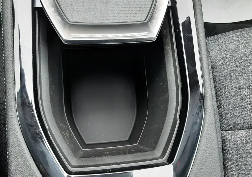 Gros plan sur la console centrale noire brillante du Renault Austral Ph.2 gris schiste, avec un espace de rangement vide.